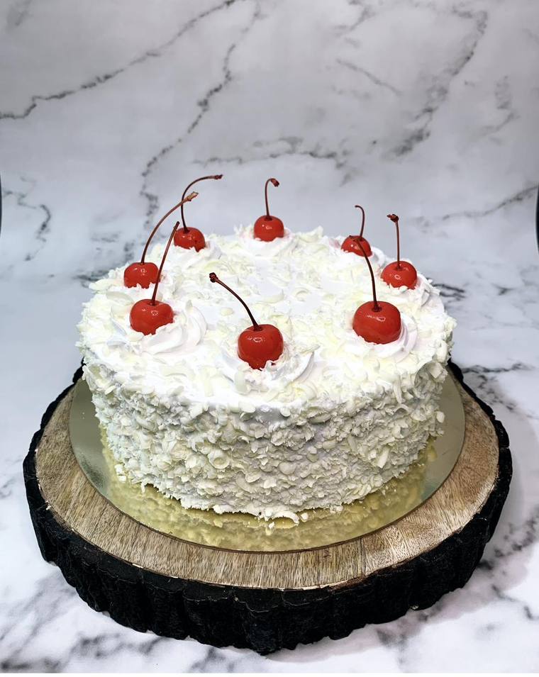 White forest cake topped with cherries
