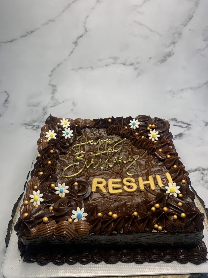 Chocolate cake piped with a name and finished with gold flowers