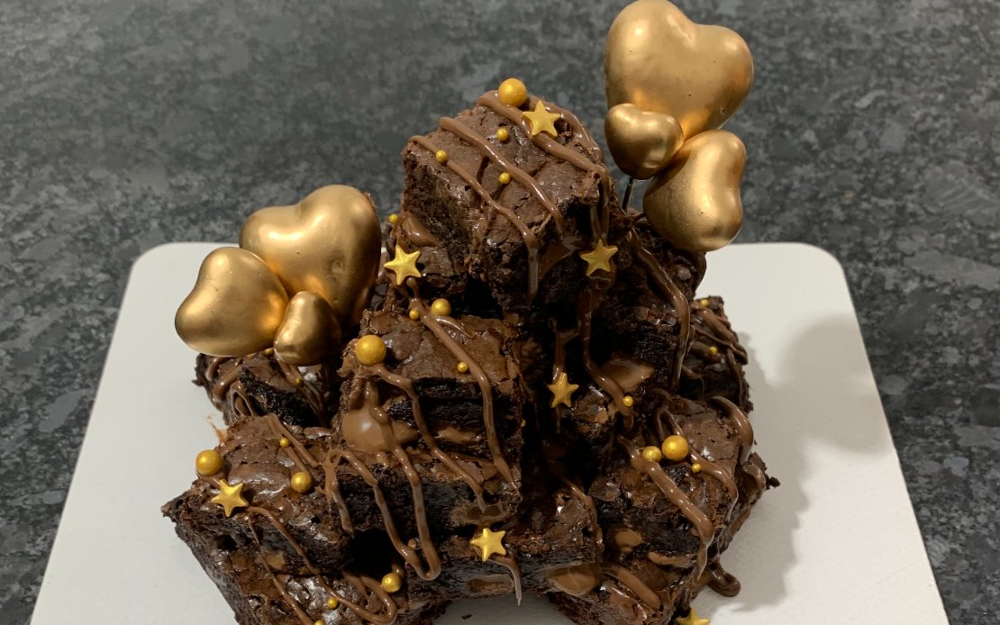 Fudgy double chocolate brownies with chocolate drizzle and gold accents